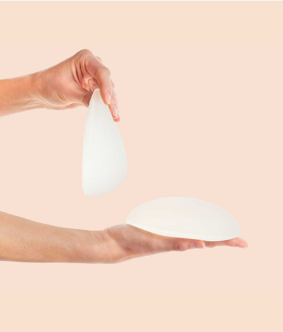 Eine Frau h&auml;lt Brustimplantate in den H&auml;nden.