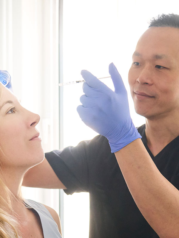 Eine blonde Frau bekommt vom Arzt eine Spritze gegen Stirnfalten.