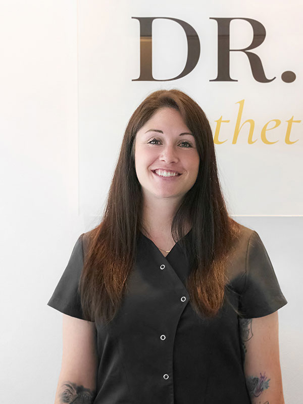 Eine Frau mit braunen mittellangen Haaren schaut l&auml;chelnd in die Kamera