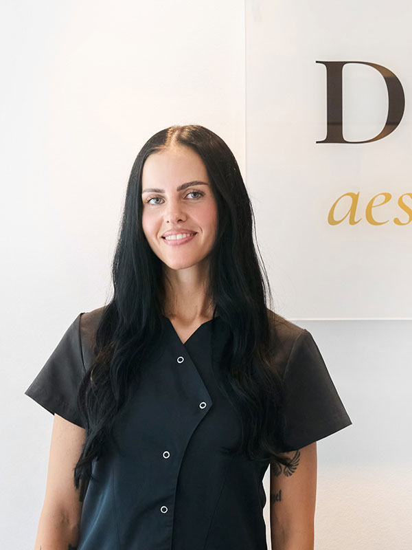 Eine Frau mit langen schwarzen Haaren schaut l&auml;chelnd in die Kamera