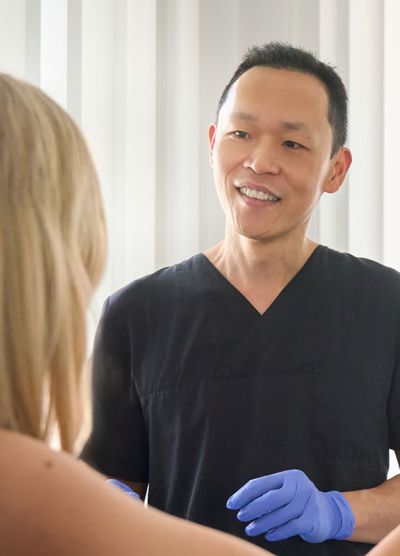 Eine blonde Patientin wird vom Arzt über den Verlauf der Behandlung informiert.